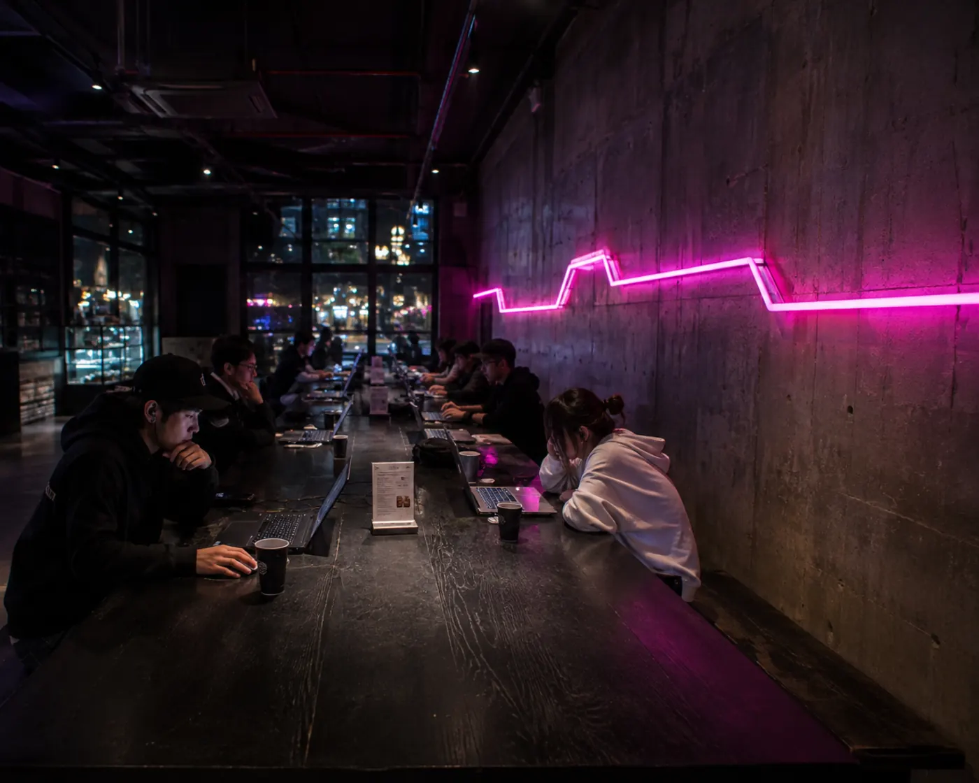 Meja coworking panjang dengan pelanggan menggunakan laptop